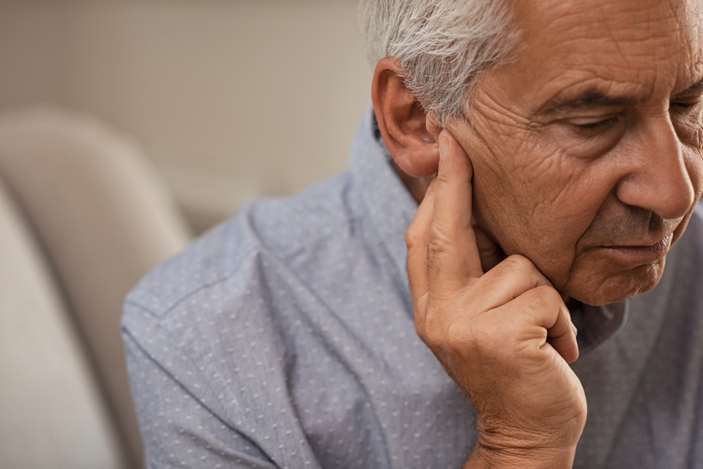 An older man experiencing discomfort in his right ear from Tinnitus
